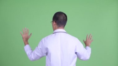Bir şeye dokunan gözlüklü Asyalı doktor.