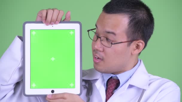 Обличчя щасливого азіатського лікаря, який показує цифрову табличку. — стокове відео