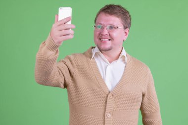 Mutlu şişman sakallı adamın portresi selfie çekiyor.