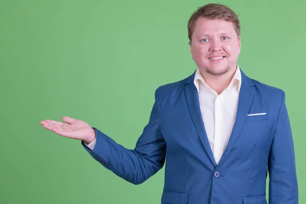 Retrato de hombre de negocios barbudo con sobrepeso feliz mostrando algo —  Fotos de Stock