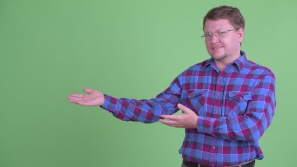 Gelukkige overgewicht bebaarde hipster man toont iets — Stockvideo