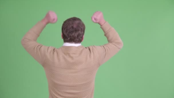 Vista posteriore di felice uomo barbuto sovrappeso con pugni alzati — Video Stock