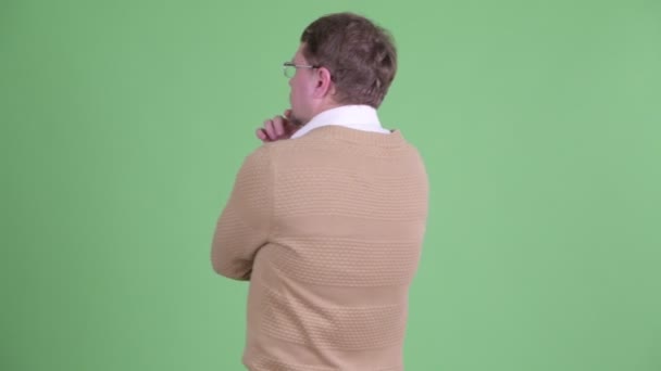 Вид сзади на бородатого человека с избыточным весом, думающего и смотрящего вокруг — стоковое видео