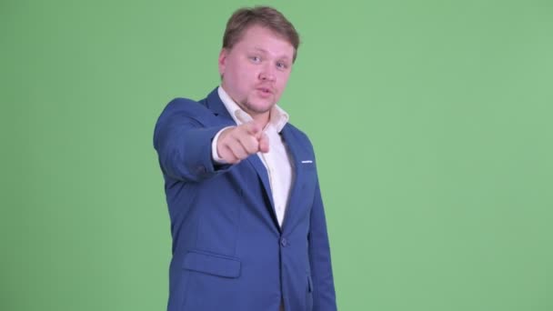 Boldog túlsúlyos szakállas üzletember, aki a kamerára mutat. — Stock videók