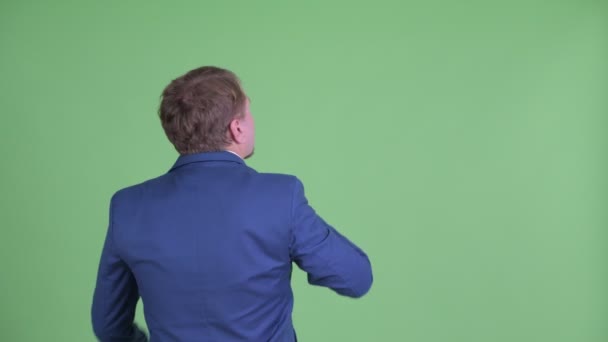 Вид сзади на толстого бородатого бизнесмена, указывающего пальцем и направляющего — стоковое видео