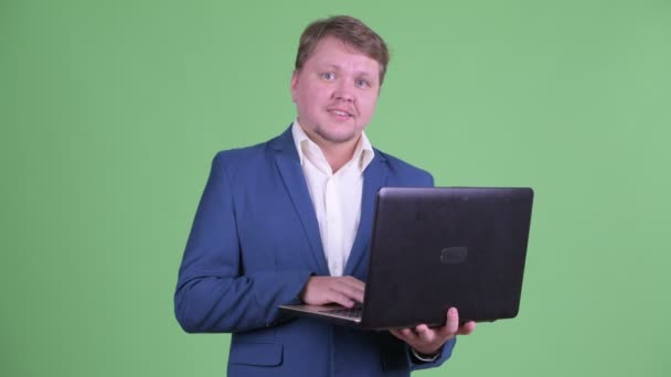 Ευτυχισμένος υπέρβαρος γενειοφόρος επιχειρηματίας μιλάει ενώ χρησιμοποιεί φορητό υπολογιστή — Αρχείο Βίντεο