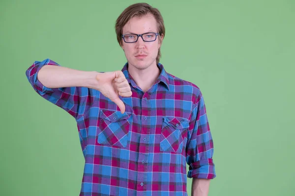 Jeune homme hipster beau avec des lunettes donnant pouces vers le bas — Photo