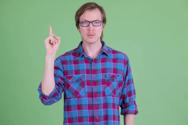 Mladý pohledný hipster muž s brýlemi ukazuje nahoru — Stock fotografie