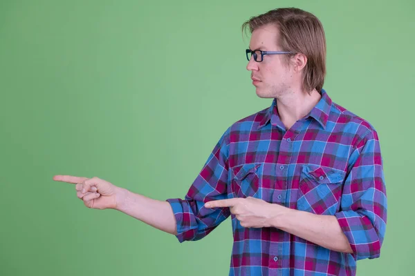 Vista del perfil del joven guapo hipster apuntando hacia un lado — Foto de Stock