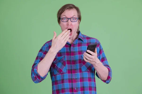 Jeune homme hipster utilisant le téléphone et l'air choqué — Photo