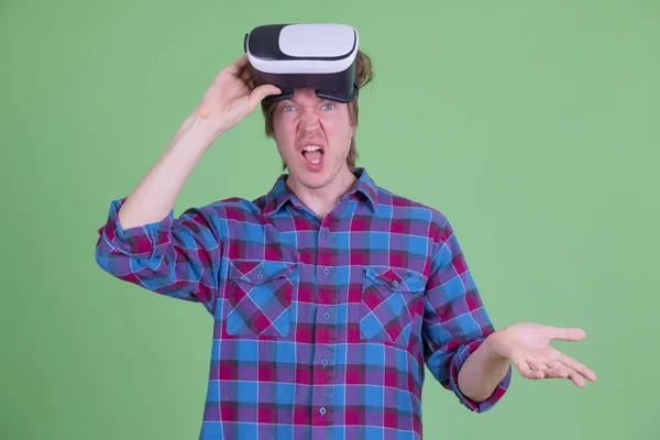 Homem jovem hipster confuso removendo headset realidade virtual e ombros encolhendo — Fotografia de Stock
