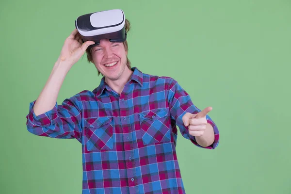 Feliz jovem hipster homem remoção virtual realidade fone de ouvido e apontando dedo — Fotografia de Stock