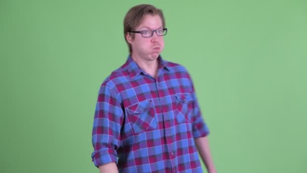 Homem jovem hipster com óculos parecendo culpado e se afastando — Vídeo de Stock