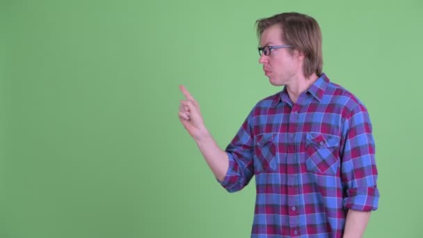 Jonge knappe hipster man raakt iets aan en kijkt schuldig — Stockvideo