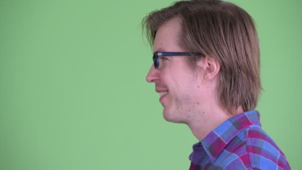 Vista del perfil de primer plano del joven hombre hipster feliz mirando a la cámara — Vídeo de stock