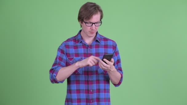 Jovem feliz hipster bonito homem usando telefone e recebendo boas notícias — Vídeo de Stock