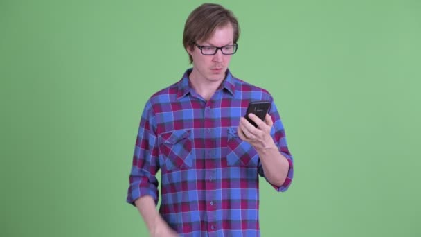 Gestresste jonge hipster man met behulp van telefoon en weglopen — Stockvideo