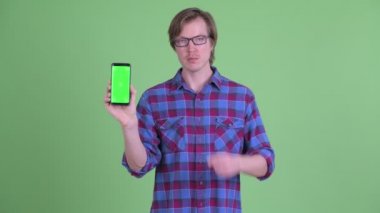 Genç, yakışıklı hippi adam işaret ediyor ve telefonu gösteriyor.