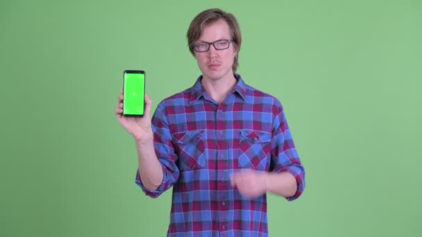 Młody przystojny hipster człowiek wskazując i pokazując telefon — Wideo stockowe