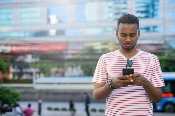 Ung stilig afrikansk skäggig man använder telefon i staden — Stockfoto