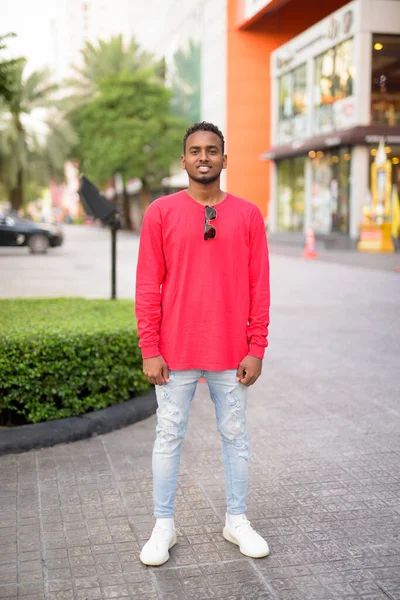 Bote de cuerpo entero de joven africano feliz sonriendo en la ciudad al aire libre — Foto de Stock