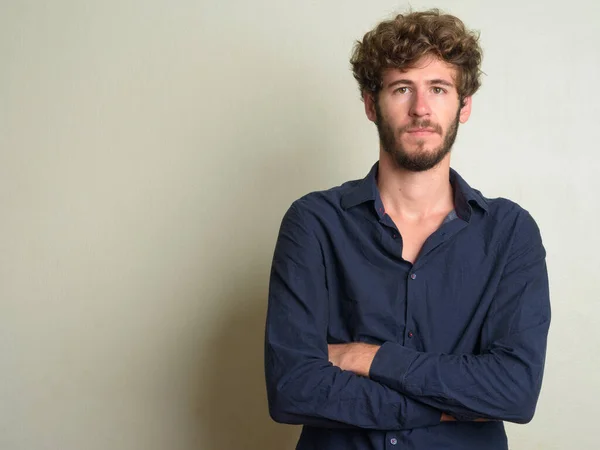 Young bearded businessman with curly hair with arms crossed