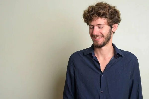 Happy young bearded businessman with curly hair thinking and looking down — ストック写真