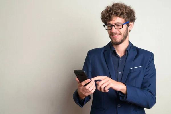 Szczęśliwy młody brodaty biznesmen z okularami za pomocą telefonu — Zdjęcie stockowe