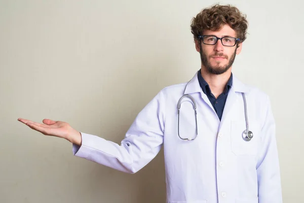 Jovem barbudo homem médico com óculos mostrando algo — Fotografia de Stock