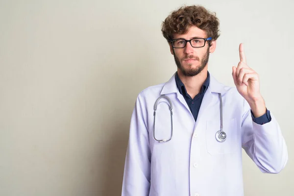 Jovem barbudo homem médico com óculos apontando para cima — Fotografia de Stock