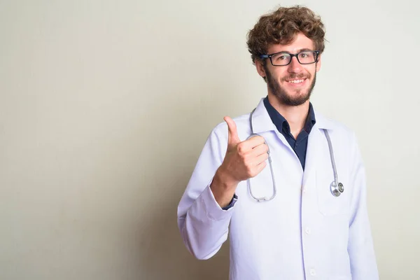 Happy young bearded man doctor with eyeglasses giving thumbs up — Stock Photo, Image