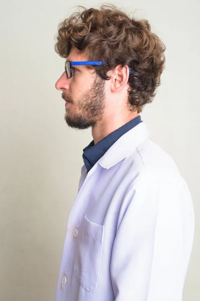 Primo piano profilo vista di giovane uomo barbuto medico con i capelli ricci indossa occhiali da vista — Foto Stock