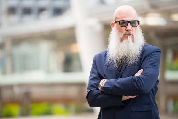 Rijpe kale zakenman met baard draagt een zonnebril in de stad buiten — Stockfoto