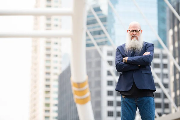 Mature bearded bald businessman with arms crossed in the city outdoors