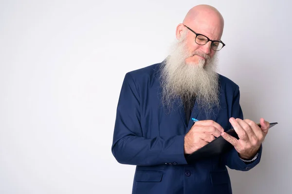 Mature bearded bald businessman with eyeglasses writing on clipboard