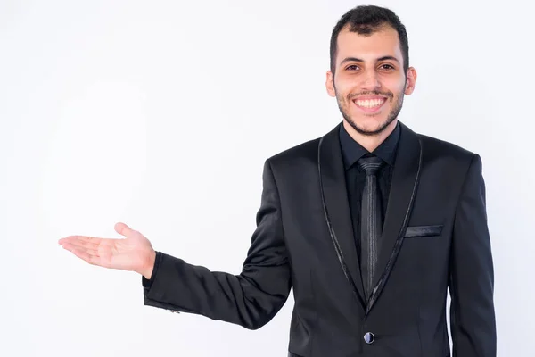 Retrato de feliz joven barbudo hombre de negocios persa en traje mostrando algo — Foto de Stock