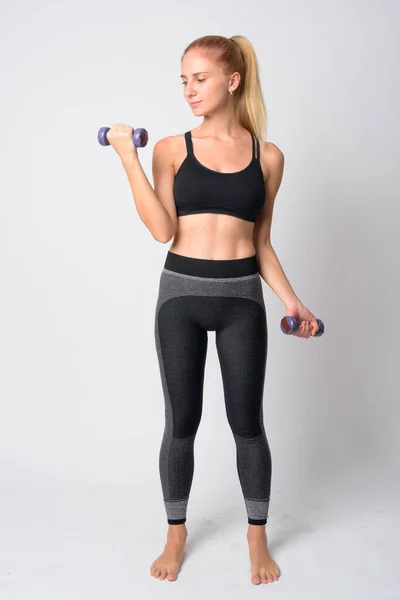 Teljes test lövés fiatal szőke nő gyakorló súlyzók készen áll a tornaterem — Stock Fotó