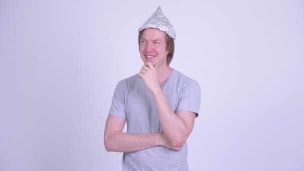 Happy young man with tinfoil hat thinking — Stock Video