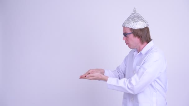 Ung man läkare med aluminiumfolie hatt skakar samtidigt som du visar något — Stockvideo