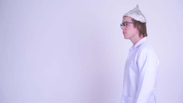 Vista del perfil del joven médico estresado con sombrero de papel de aluminio que parece asustado — Vídeos de Stock