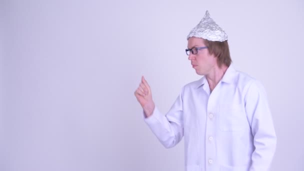 Молодий чоловік лікар з фольгою капелюх ламає пальці і виглядає шоковано — стокове відео