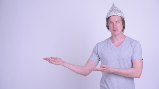 Joven con sombrero de papel de aluminio mostrando algo — Vídeos de Stock