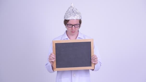 Young man doctor with tinfoil hat holding blackboard — Stock Video