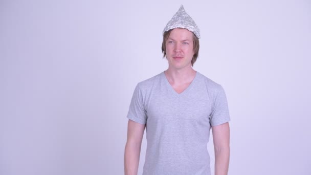 Ευτυχισμένος νεαρός με καπέλο από αλουμινόχαρτο να κουνάει το χέρι — Αρχείο Βίντεο