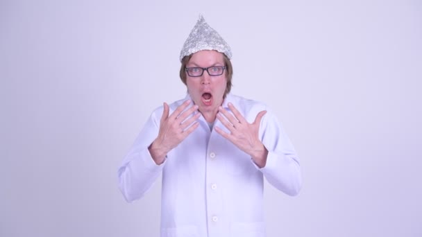 Joven doctor con sombrero de papel de aluminio mirando sorprendido — Vídeos de Stock