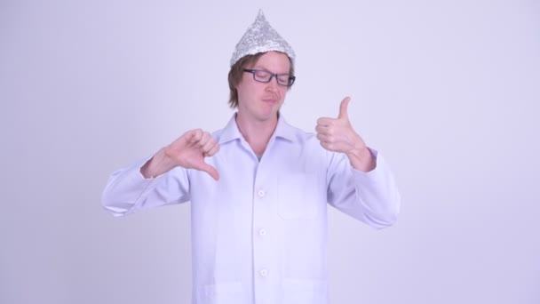 Молодой человек врач в шляпе из фольги выбор между большим и большим пальцами вниз — стоковое видео