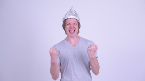 Feliz joven con sombrero de papel de aluminio recibiendo buenas noticias — Vídeos de Stock