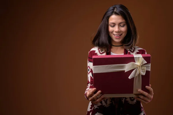 Portrait of beautiful multi ethnic woman holding gift box ready for winter