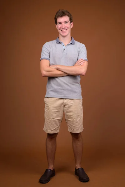 Jonge knappe man met grijs shirt tegen bruine achtergrond — Stockfoto