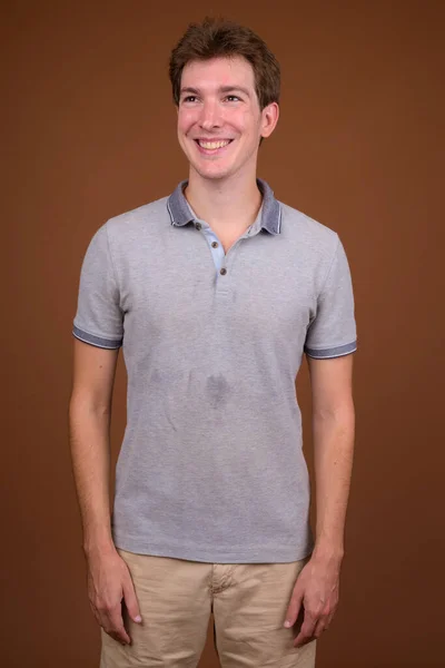 Young handsome man wearing gray shirt against brown background — Stock Photo, Image